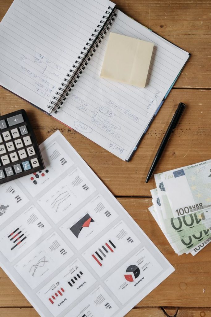 Mastering the First Impression: Your intriguing post title goes here High-angle view of a financial workspace with charts, Euro bills, calculator, and notebook on a wooden desk.
